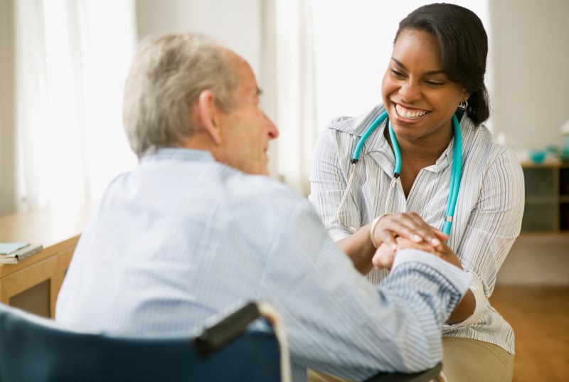 Clinician smiling at patient and holding hands